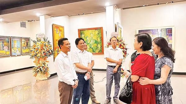 Họa sĩ Trần Giang Nam (ngoài cùng bên trái) trao đổi với người yêu tranh khắc gỗ tại triển lãm cá nhân ở Hà Nội.