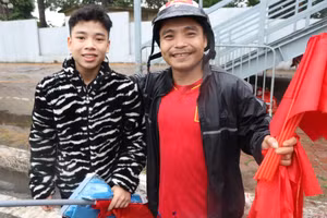Hai cha con anh Nam bán cờ với hy vọng có thêm tiền để mua vé vào sân. (ẢNH: Sơn Bách)