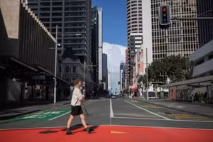 Một phụ nữ đeo khẩu trang đi trên đường phố Auckland, New Zealand ngày 18/8. 