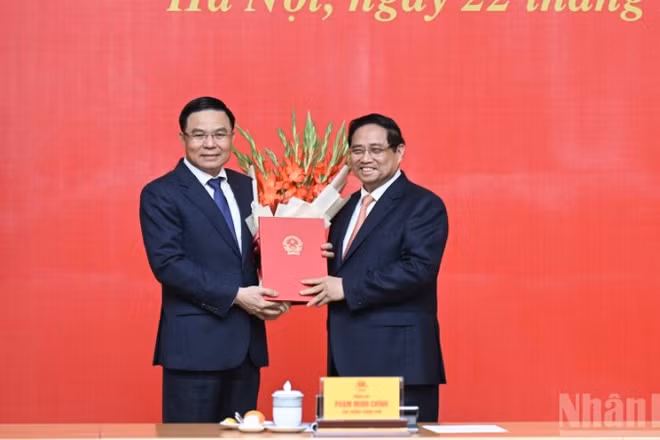 Bí thư Đảng ủy Chính phủ, Thủ tướng Chính phủ Phạm Minh Chính trao Quyết định bổ nhiệm, tặng hoa chúc mừng đồng chí Lê Mạnh Hùng, Quyền Bộ trưởng Công thương. (Ảnh: TRẦN HẢI)