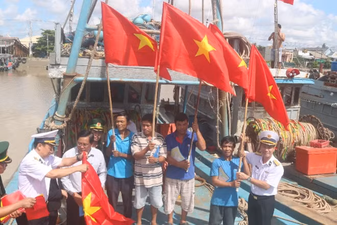 Ngư dân xã Đại An, tỉnh Vĩnh Long được cán bộ, chiến sĩ Hải quân Vùng 2 trao tặng cờ Tổ quốc.