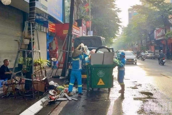 Công nhân môi trường dọn dẹp, thu gom rác sau mưa bão trên phố Khâm Thiên (Hà Nội). 
