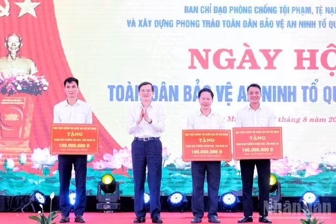 Đồng chí Đoàn Minh Huấn, Ủy viên Bộ Chính trị, Giám đốc Học viện Chính trị quốc gia Hồ Chí Minh tặng quà cho nhân dân các phường: Hoàng Mai, Tân Mai, Quỳnh Mai (Nghệ An). (Ảnh: PT)