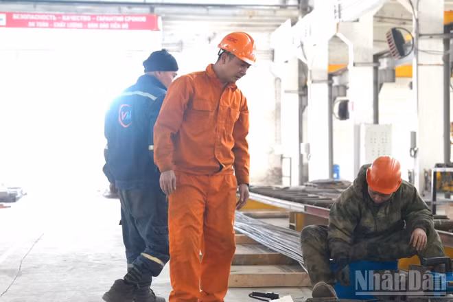 Anh Trần Văn Sơn (áo cam) trong xưởng làm việc. (Ảnh: THANH THỂ)
