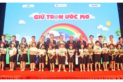 Phó Thủ tướng Trương Hòa Bình và các đại biểu trao tượng trưng mũ bảo hiểm đạt chuẩn cho các học sinh lớp một tại lễ công bố chương trình “Giữ trọn ước mơ” ngày 3-7.