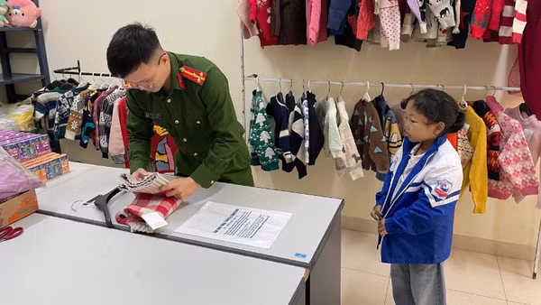 Gấp áo ấm tặng trẻ nhỏ đến làm thẻ căn cước. (Ảnh: HƯƠNG LAN).