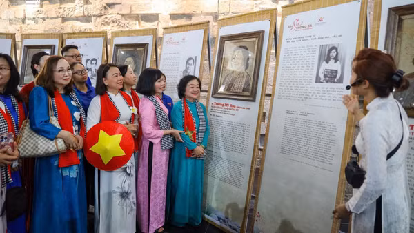 Nguyên Phó chủ tịch nước Trương Mỹ Hoa (áo dài xanh, bên phải) bên tác phẩm chân dung mình được nghệ nhân tạo tác trên lá sen Việt Nam. (Ảnh: Ban tổ chức cung cấp)