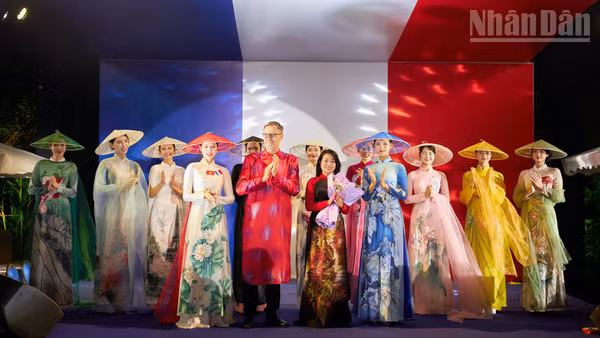 Đại sứ Pháp Olivier Brochet (áo dài đỏ) chúc mừng nhà thiết kế Hàn Phượng (cầm hoa) sau màn trình diễn áo dài.