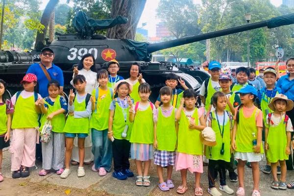Chị Nguyên (áo dài trắng) cùng cộng sự đưa các em nhỏ đến thăm Dinh Độc Lập để tìm hiểu về lịch sử dân tộc. ẢNH: Tiệp Phạm