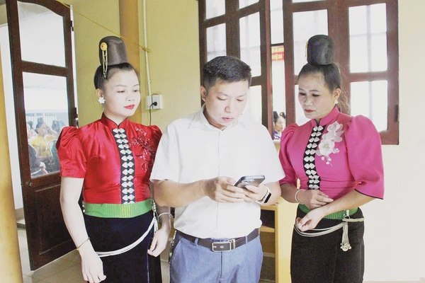 Cán bộ phường Chiềng Cơi hướng dẫn người dân cài đặt và sử dụng ứng dụng số trên điện thoại. Ảnh: BSL