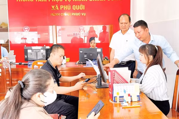 Cán bộ Trung tâm Phục vụ hành chính công xã Phú Quới hướng dẫn người dân làm thủ tục hành chính. 