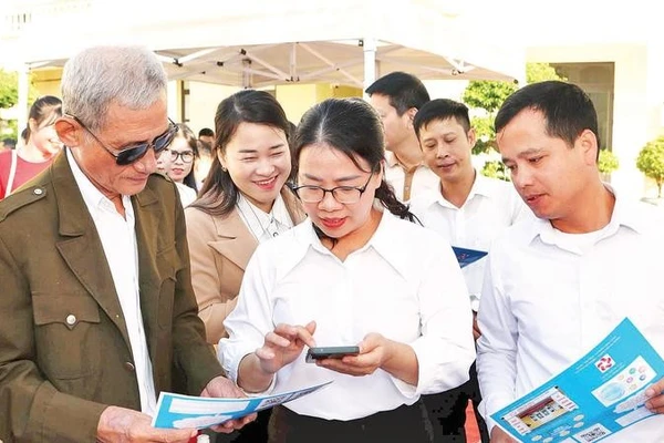 Cán bộ phường An Phong hướng dẫn người dân lấy số thứ tự giải quyết thủ tục hành chính trên VNeID.