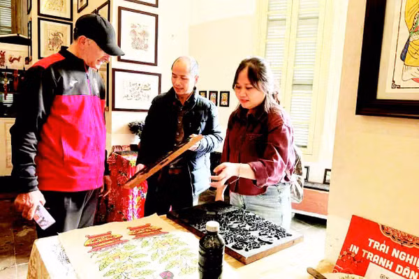 Võ Ca Dao hướng dẫn cho du khách nước ngoài trải nghiệm in tranh mộc bản.