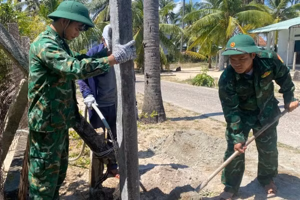 Cán bộ, chiến sĩ Đồn Biên phòng Xuân Hòa phối hợp lực lượng địa phương tham gia dựng cột điện, hoàn thiện các hạng mục của mô hình “Thắp sáng đường quê” tại Thôn 4, xã Xuân Lộc.