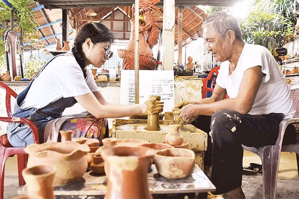 Du khách trải nghiệm làm đồ gốm khi tới thăm làng Thanh Hà.