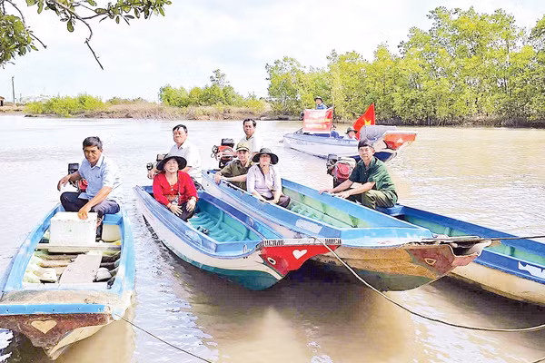 Cán bộ đến tận những căn nhà dân dựng ven sông để trao thẻ cử tri, mang lại niềm vui và sự an tâm cho người dân vùng sâu.