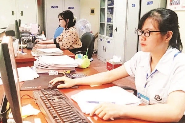 Cán bộ Đội Thuế thành phố Bắc Giang rà soát hồ sơ để thực hiện giảm tiền thuê đất cho doanh nghiệp. (Ảnh MINH LINH)