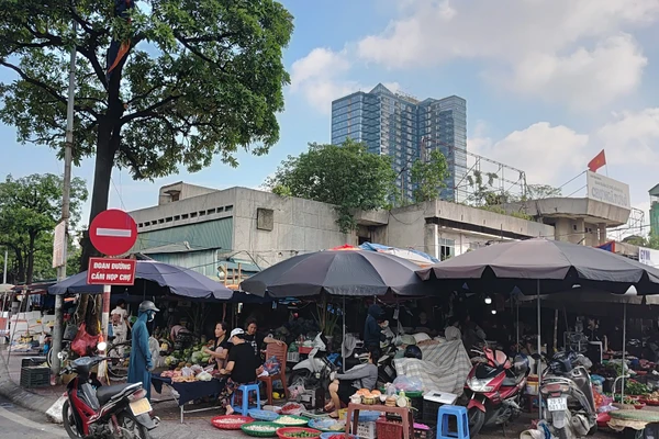 Các quầy, sạp bên trong chợ Ngã Tư Sở bị bỏ không, nhưng nhiều người dân lại tràn ra vỉa hè để bán hàng. (Ảnh VĂN HỌC) 
