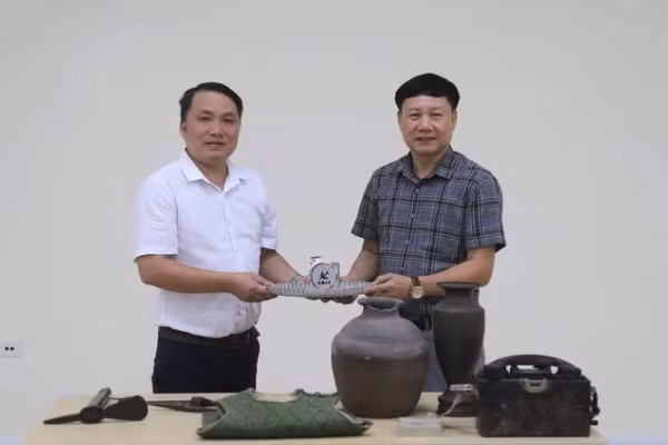 Phó Giám đốc Bảo tàng tỉnh Quảng Trị Mai Thế Trung (áo trắng) trao hiện vật, tư liệu phục vụ xây dựng Bảo tàng Đảng Cộng sản Việt Nam 