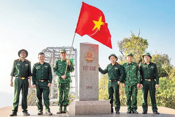 Thượng úy Lục Vĩnh Lương (người cầm cờ) cùng tác giả và đoàn công tác tại Cột mốc số 0 - Ngã ba biên giới A Pa Chải - Cực tây Tổ quốc.