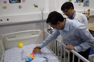 Thứ trưởng Bộ Y tế Nguyễn Tri Thức thăm cháu bé bị bạo hành tại Bệnh viện Nhi đồng 1, Thành phố Hồ Chí Minh. (Ảnh: ĐỖ BÁ)