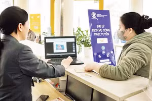 Người dân được nhân viên hướng dẫn làm thủ tục hành chính tại các đại lý dịch vụ công trực tuyến của thành phố Hà Nội. (Ảnh: NGUYÊN TRANG)
