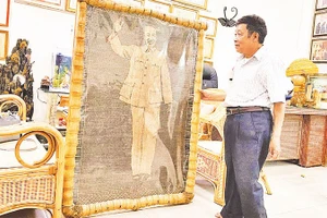 Nghệ nhân nhân dân Nguyễn Văn Trung bên bức chân dung Bác Hồ bằng mây tre vừa hoàn thiện.