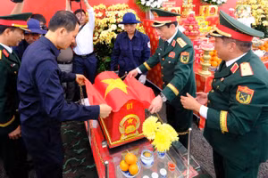 Các đại biểu thực hiện nghi lễ phủ cờ Tổ quốc lên hài cốt liệt sĩ vừa quy tập tại xã Minh Đức, thành phố Đồng Nai.