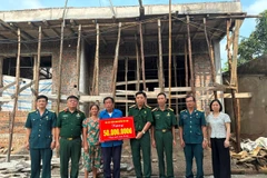 Cựu chiến binh Phạm Văn Lượng (đứng giữa) nhận hỗ trợ xây nhà mới. (Ảnh NGỌC LAN)