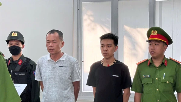 Đặng Trần Quốc Vũ (áo trắng) và Đào Năng Nghĩa (áo đen) nghe đọc lệnh tạm giữ hình sự.