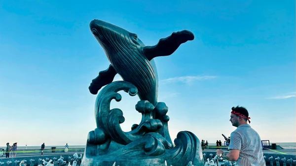 Du khách nước ngoài bên tượng Cá Ông