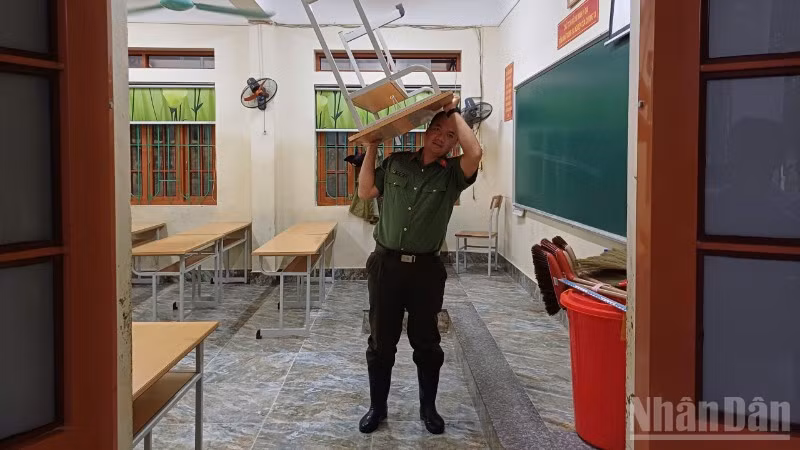 Lực lượng Công an tham gia vận chuyển bàn, ghế ở trường học lên chỗ cao.