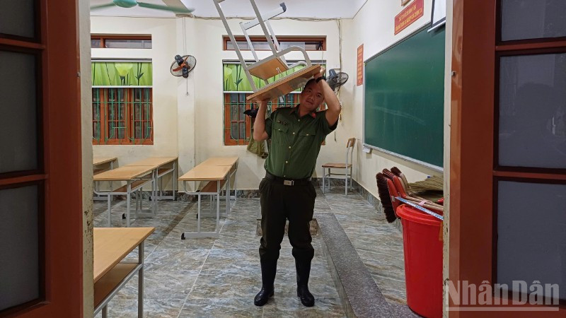 Lực lượng Công an tham gia vận chuyển bàn, ghế ở trường học lên chỗ cao.