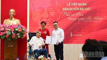 Tổng Biên tập Lê Quốc Minh nhận bản thảo bài hát Như có Bác trong ngày đại thắng có chữ ký đề tặng của nhạc sĩ Phạm Tuyên. (Ảnh: THÀNH ĐẠT)