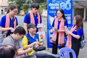 Sinh viên Học viện Cán bộ Thành phố Hồ Chí Minh trao đổi, hướng dẫn người dân đến giao dịch hành chính tại Ủy ban nhân dân phường Bình Thạnh.