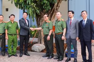 Lãnh đạo nhà trường và đại diện đoàn công tác chụp ảnh bên cây nhãn trồng lưu niệm. 