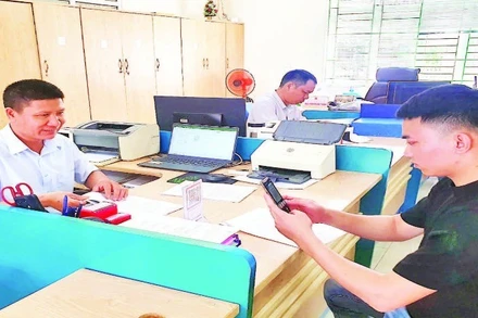 Cán bộ của Trung tâm Hành chính công huyện Hải Hà hướng dẫn người dân cài đặt ứng dụng thanh toán không dùng tiền mặt trên điện thoại thông minh.