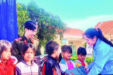 Chị Huỳnh Thị Mai Yến trao áo ấm tặng các em học sinh đồng bào dân tộc thiểu số.