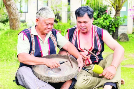 Nghệ nhân Ưu tú Đinh Dôch (bên trái) hướng dẫn kỹ thuật chỉnh chiêng cho học viên. (Ảnh LAM NGUYÊN)