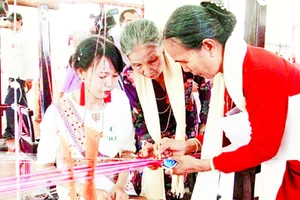 Nghệ nhân Đạt Thị Nam (áo cam) truyền dạy kỹ thuật dệt hoa văn Chăm cổ cho phụ nữ Chăm.