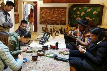 Du khách nước ngoài trải nghiệm làm sơn mài ở làng Hạ Thái. (Ảnh: LÊ BÍCH)