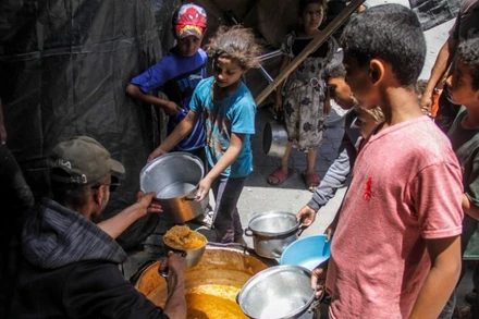 Các em nhỏ nhận thực phẩm cứu trợ tại Jabalia, Dải Gaza. (Ảnh: THX/TTXVN)