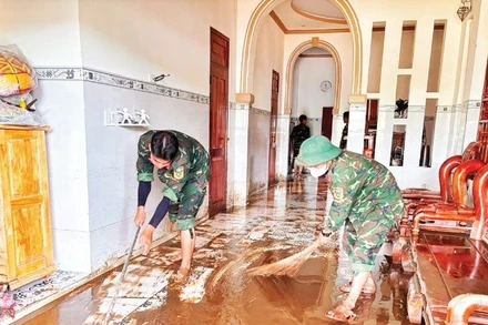 Chiến sĩ Trung đoàn bộ binh 812 giúp đồng bào Chăm ở thôn Lâm Giang (xã Hàm Thuận Bắc) dọn bùn.