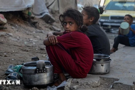 Trẻ em ngồi chờ nhận thức ăn cứu trợ ở thành phố Gaza. (Ảnh: THX/TTXVN)