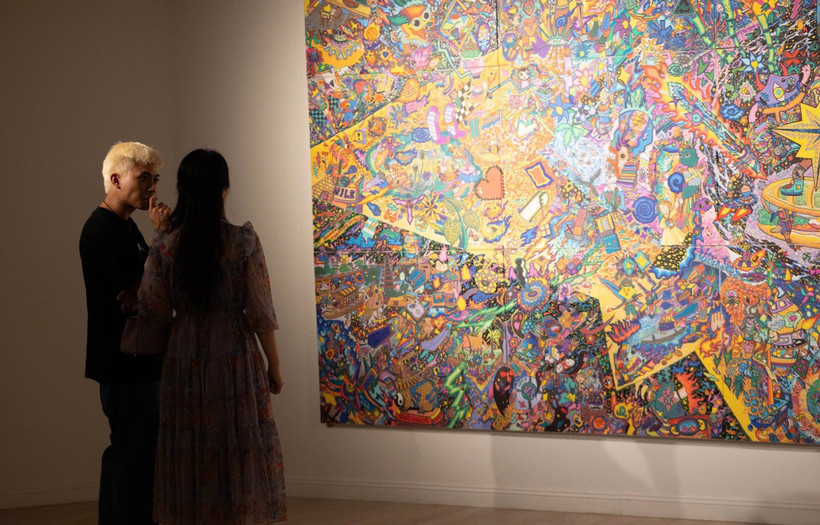 Họa sĩ Hoàng Anh Trung chia sẻ với phóng viên về quá trình sáng tạo. (Ảnh: Mơ Art Space)