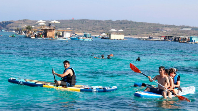 Du khách trải nghiệm lặn biển ngắm san hô, chèo sup tại khu vực Bãi Cạn, Phú Quý. (Ảnh: TTXVN)