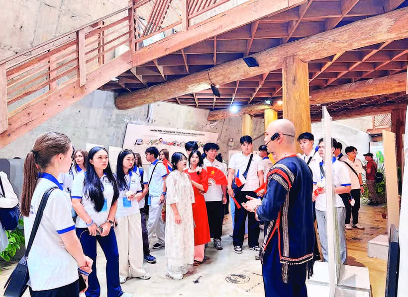 1. Các thanh niên kiều bào tham quan nhà dài truyền thống của dân tộc Ê Đê tại Bảo tàng Thế giới cà-phê.