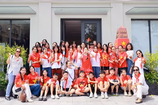 Các em học sinh chụp ảnh lưu niệm tại mô hình cột mốc Trường Sa ở Trung tâm Thông tin văn hóa Hồ Gươm.