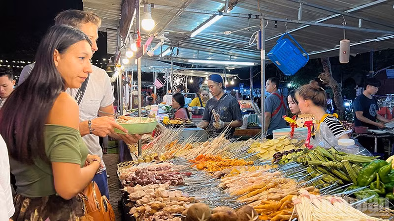 Ảnh minh họa: Khách du lịch nước ngoài hào hứng khám phá các món ăn Lào. (Ảnh: TRỊNH DŨNG)