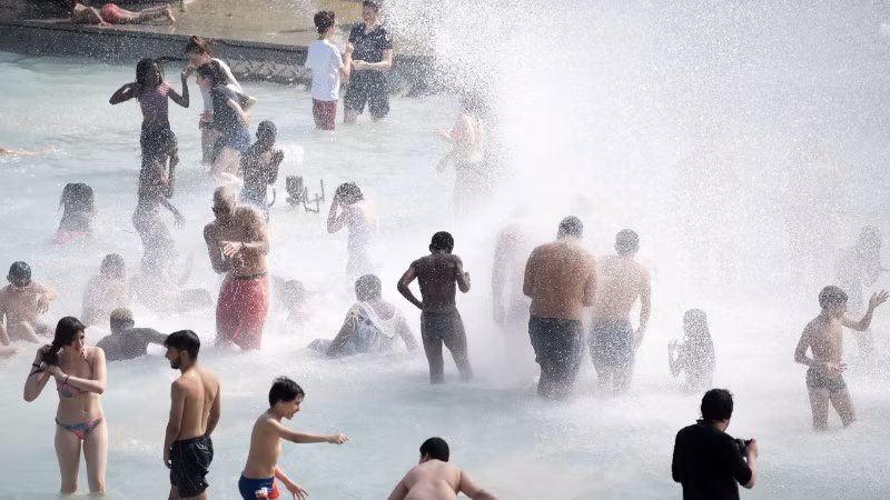 Người dân tránh nóng tại đài phun nước ở Paris, Pháp. Ảnh: THX/TTXVN